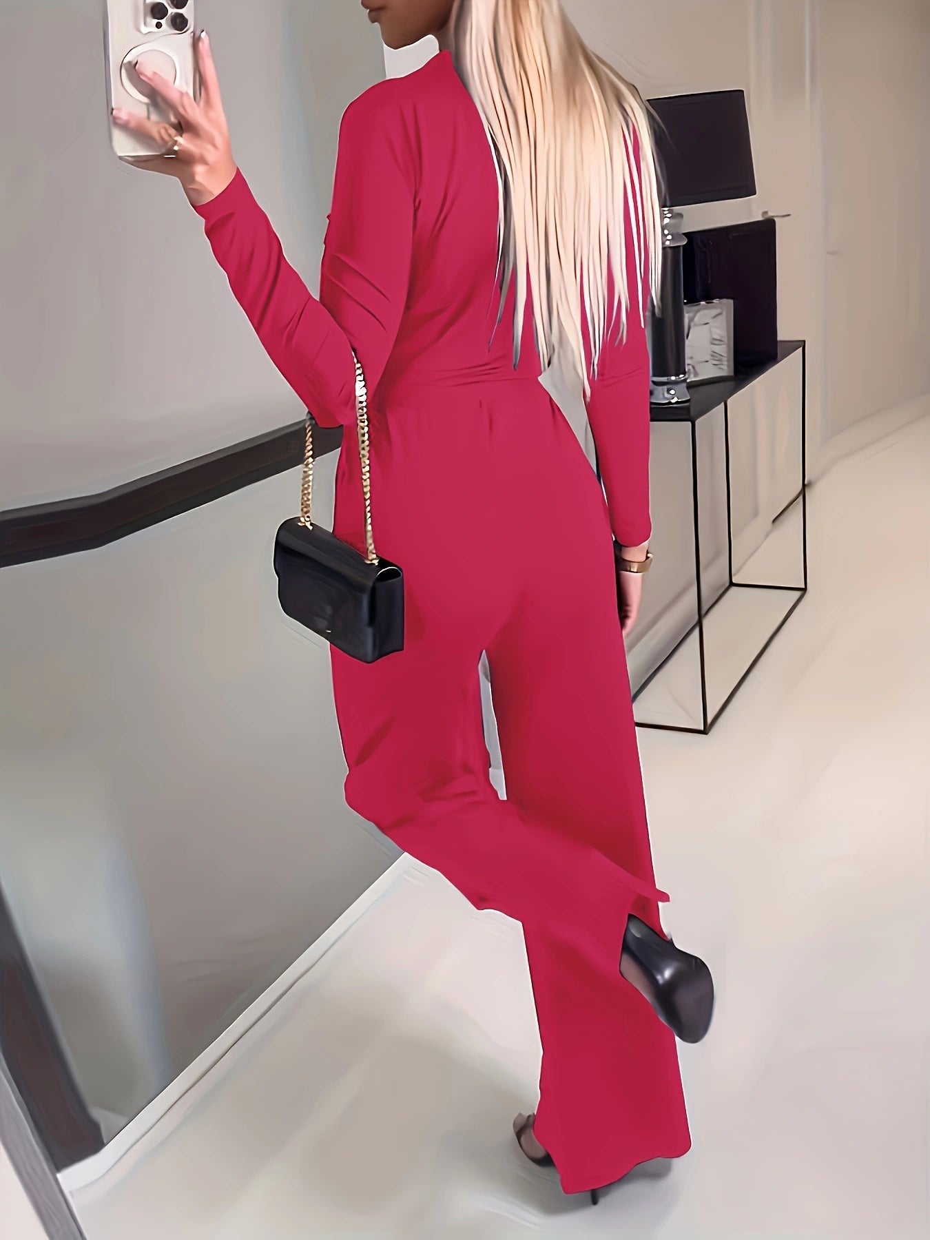 Person wearing a red outfit with a black handbag in a modern interior setting